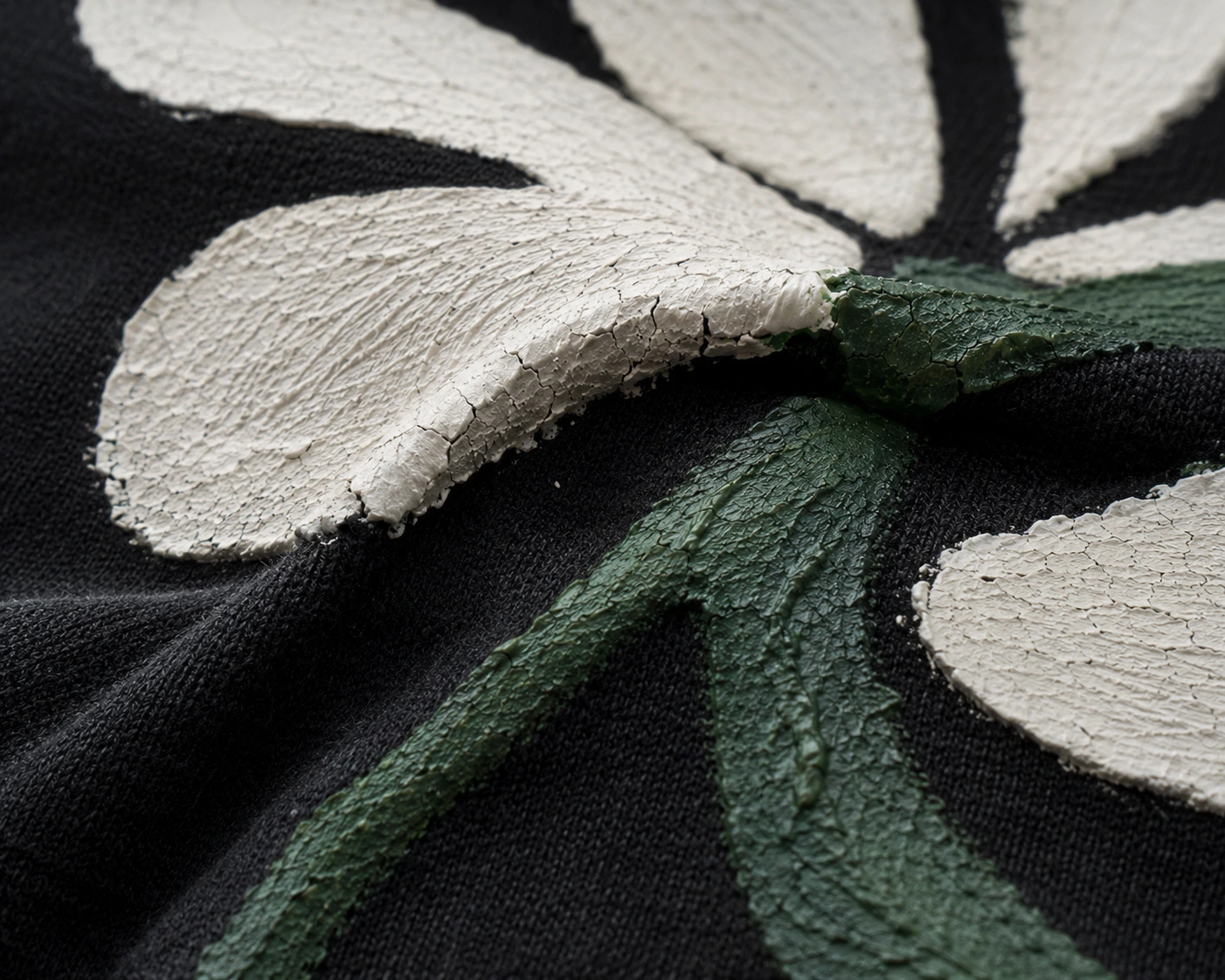 Cracked fabric paint close-up on black clothing after washing
