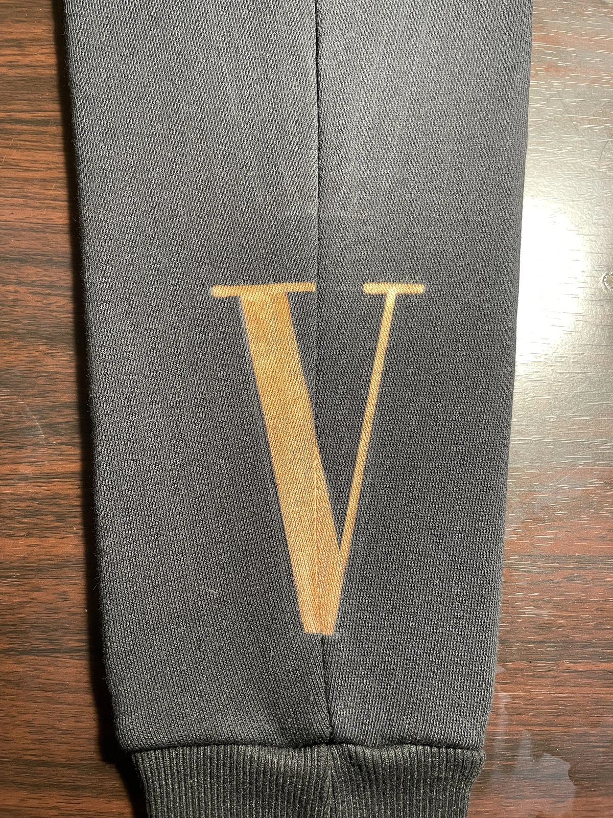 Schwarzer Kapuzenpulloverärmel mit einem handgemalten Buchstaben V verziert, der den Sieg symbolisiert.