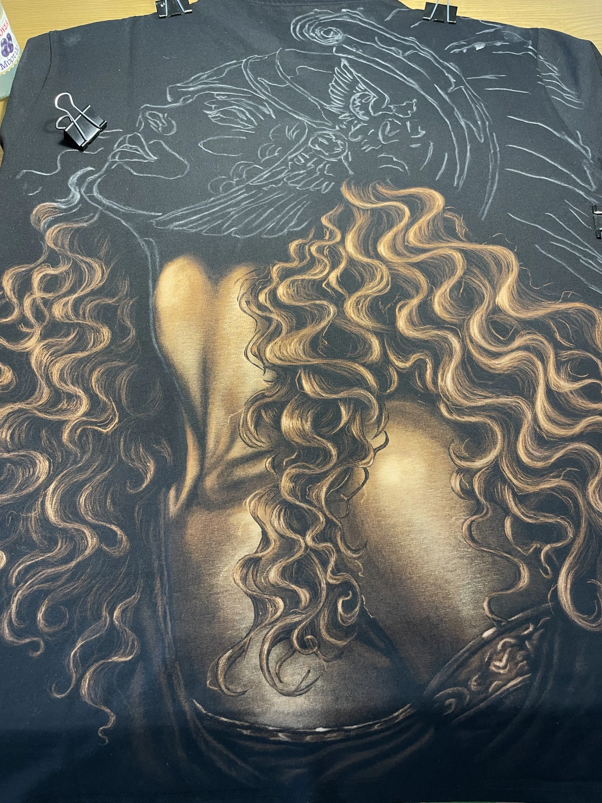 Artist creating custom bleach art clothing by hand on a black cotton T-shirt