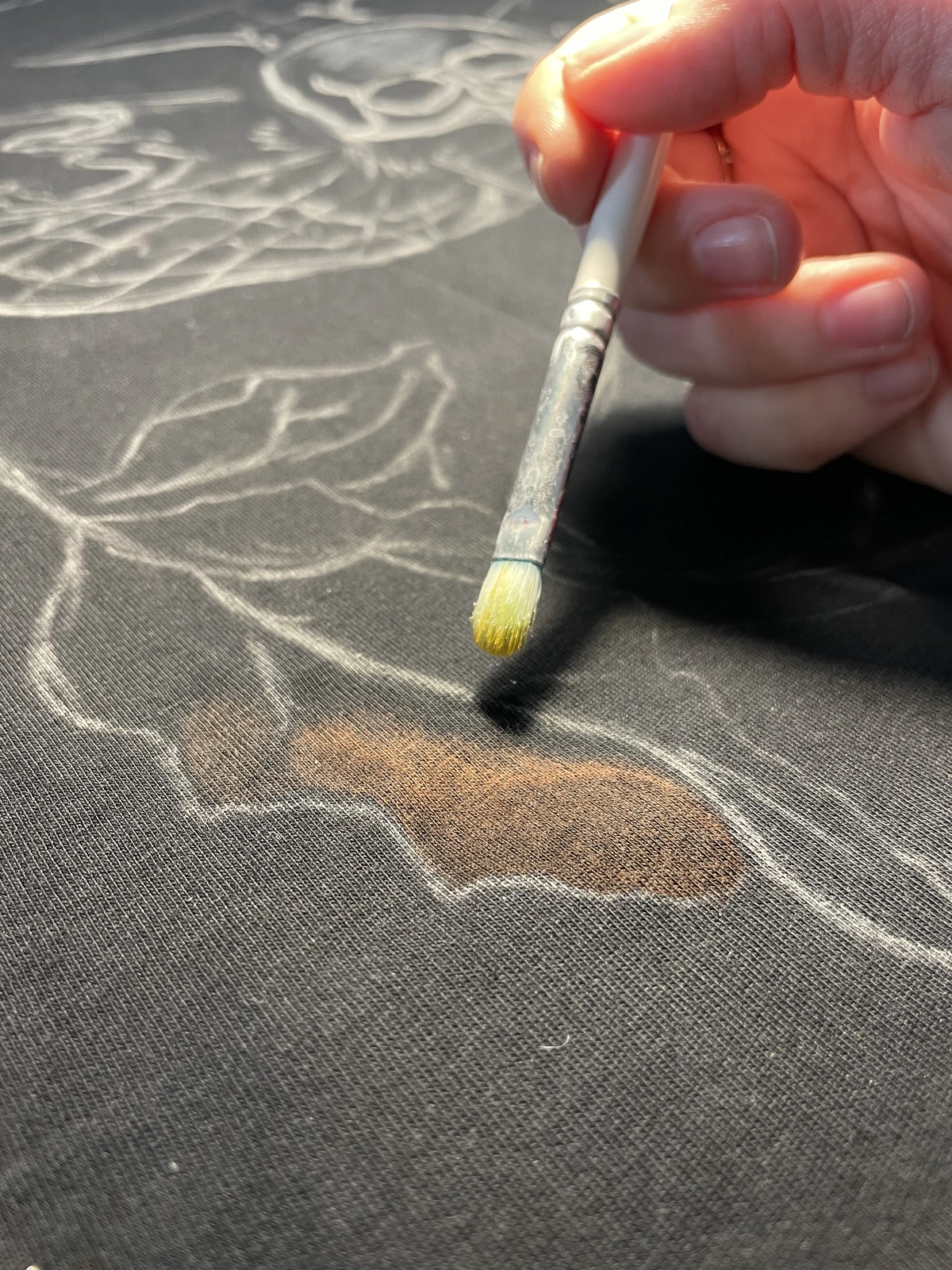 Brush applying bleach to a shirt design outline