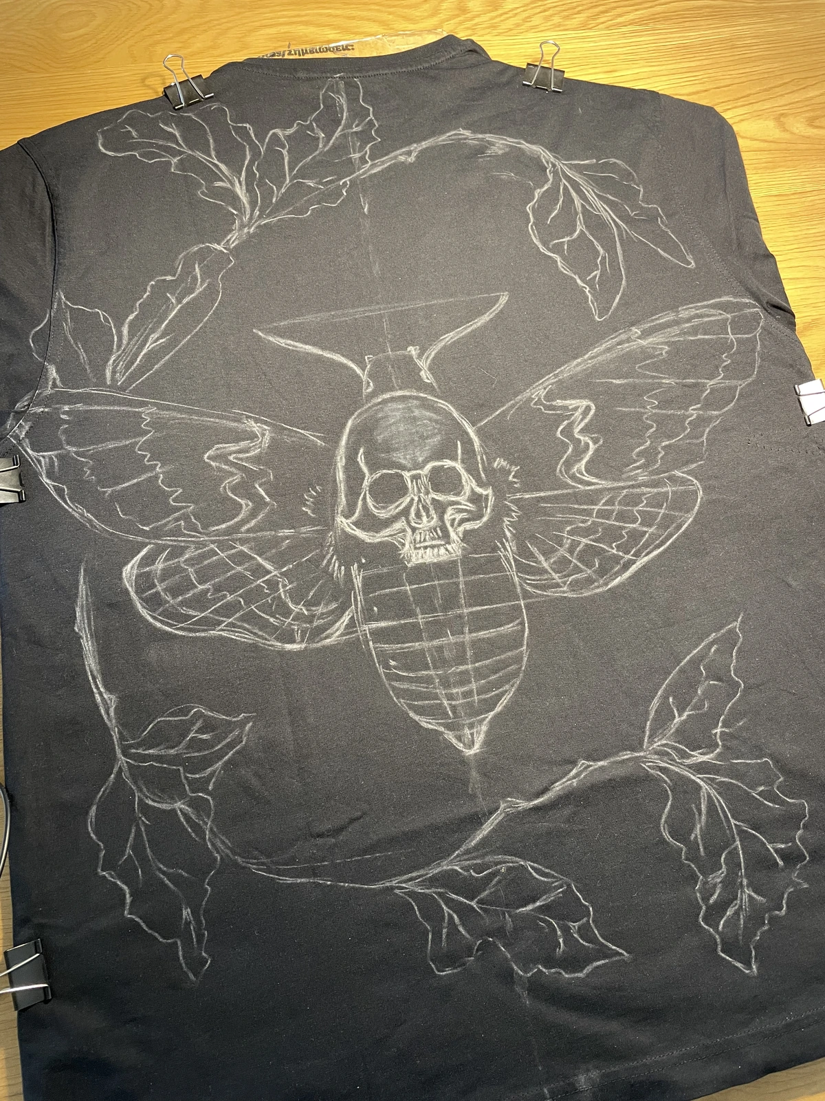 Stencil placed on a black shirt for a bleach design
