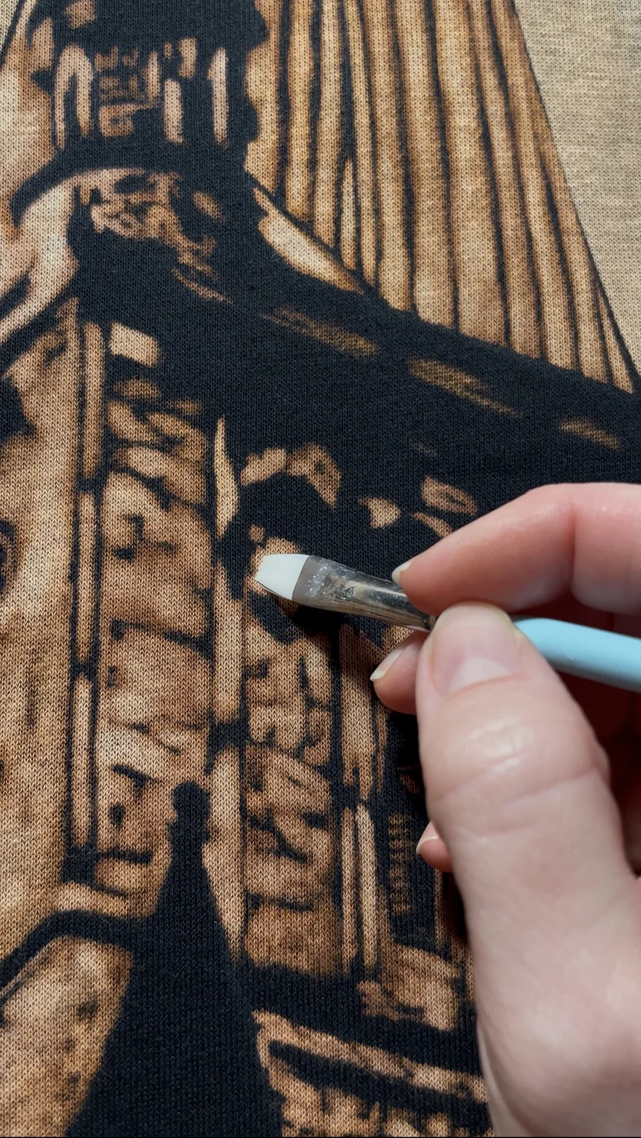 Applying bleach with a brush on a dark shirt