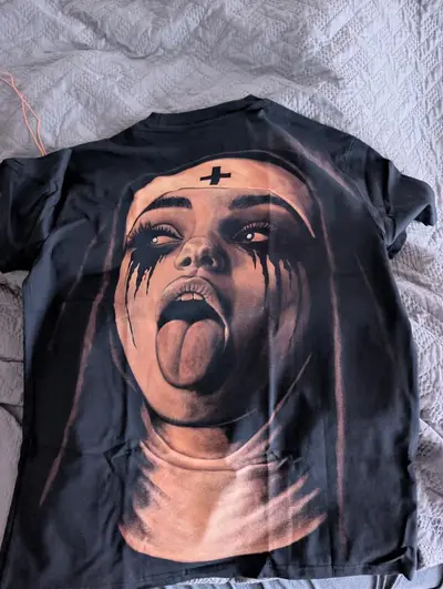 Customer photo of a newly received hand-painted t-shirt featuring a rebellious nun design with tongue out