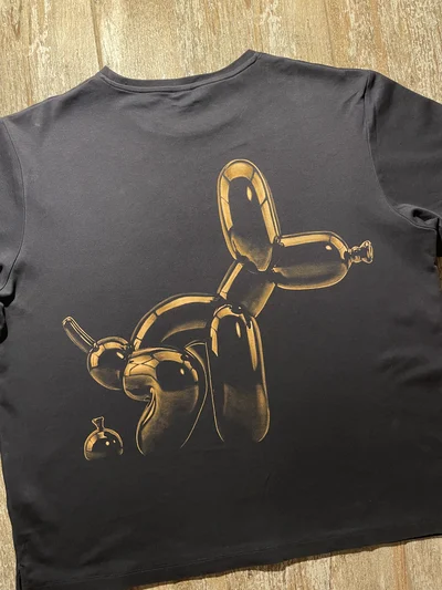 Close-up of the back balloon dog bleach art design showing the playful hand-painted illustration on black cotton fabric