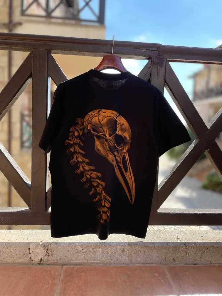 Daylight full view of a t-shirt with a bird skeleton illustration on the back