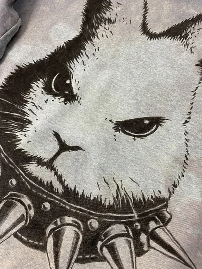Close-up of angry bunny hand-painted artwork with spiked collar on blue sweatshirt