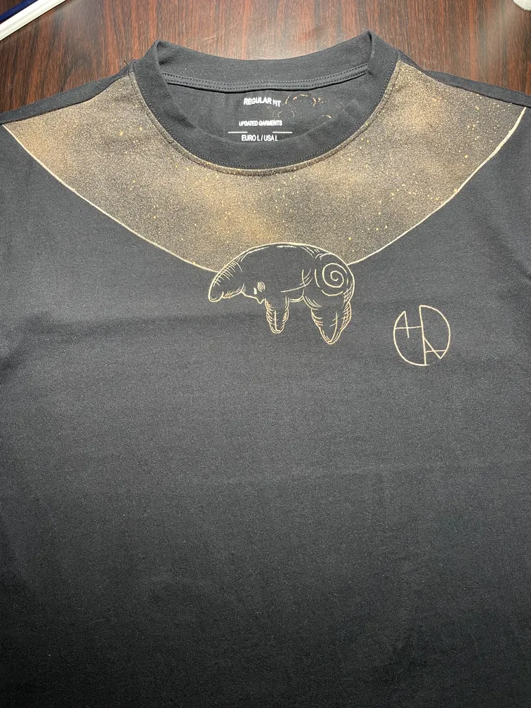 Front view of a t-shirt with the Helen Oben Art logo and a sleeping star illustration