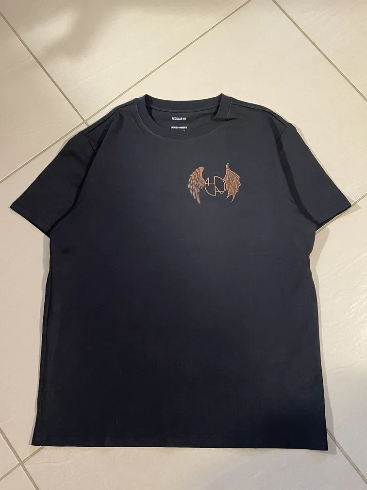 Front view of a t-shirt with the Helen Oben Art logo framed by angel and demon wings