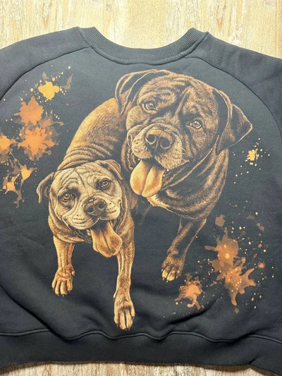 Nähere Rückansicht mit zwei individuellen Hundeporträts nach persönlichen Tierfotos auf einem schwarzen Sweatshirt