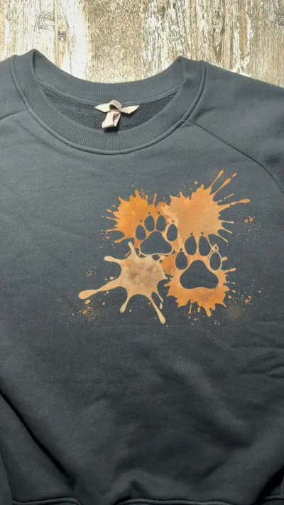 Video mit dem minimalistischen Hundepfoten Design auf Herzhöhe an der Vorderseite eines schwarzen Sweatshirts
