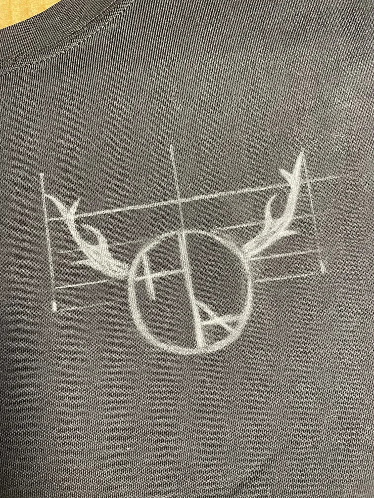 Chalk sketch of the Helen Oben Art logo on the front of the t-shirt