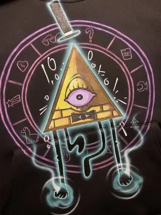 Close-up of a triangle demon illustration inspired by Bill Cipher painted on a hoodie