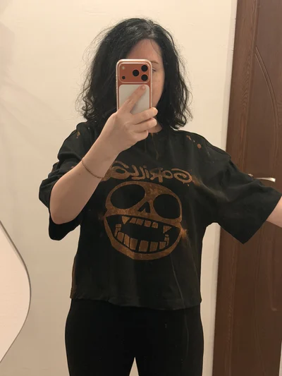 Gorillaz Totenkopf Logo und Bandname auf der Vorderseite des von einem Model getragenen Crop Tops
