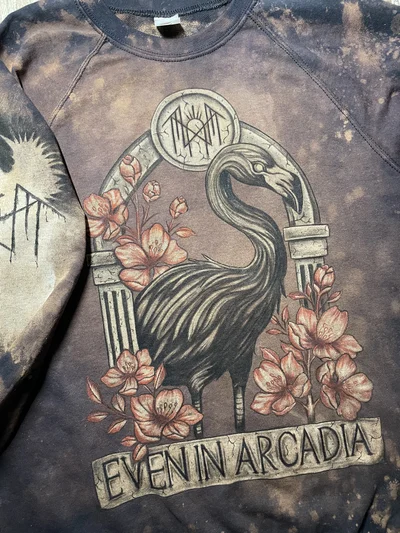 Close up of the hand painted flamingo, flowers and Even In Arcadia front design on a black sweatshirt