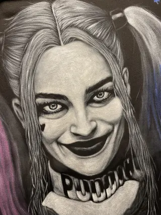 Close-up of a hand-painted comic villain–inspired face with pink and blue details on a hoodie