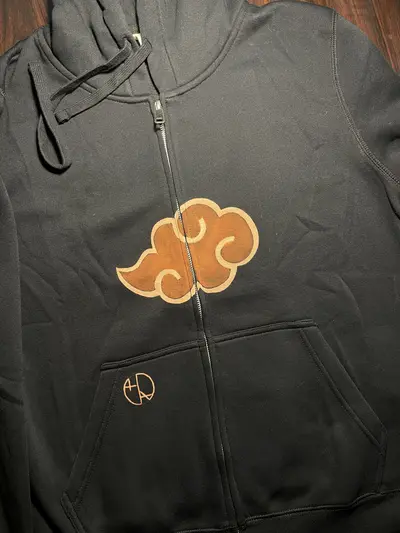 Front view of a zip hoodie showing the red clouds emblem and Helen Oben Art logo