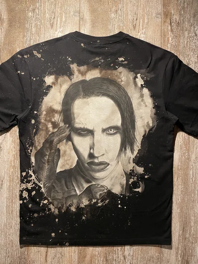 Full back view of a black Marilyn Manson T-shirt with a hand-painted portrait on a bleached background