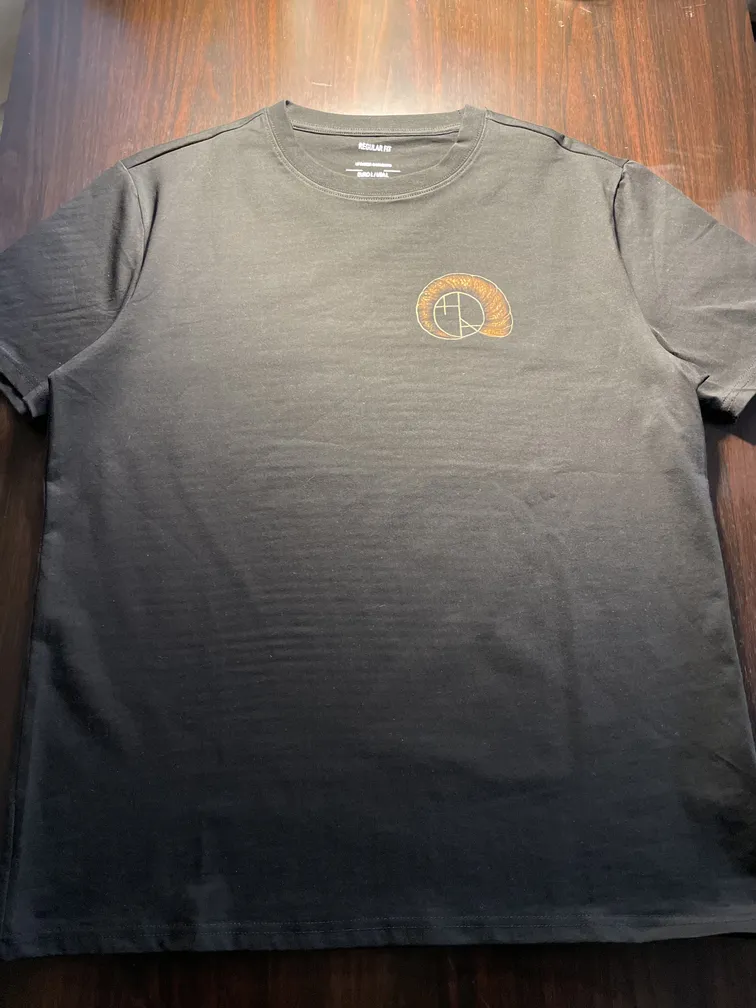 Front view of a t-shirt with a shell-shaped artist logo