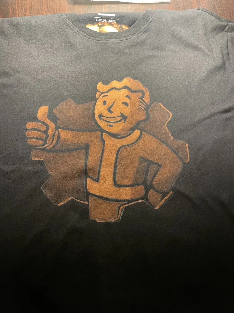 Front view of a t-shirt with a retro nuclear mascot illustration giving a thumbs-up