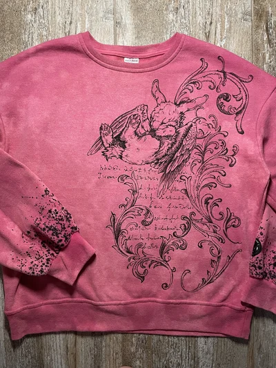 Vollständige Vorderansicht eines rosa Cybersigilism-Sweatshirts mit handgemaltem geflügeltem Hasen und schwarzen Ornamenten