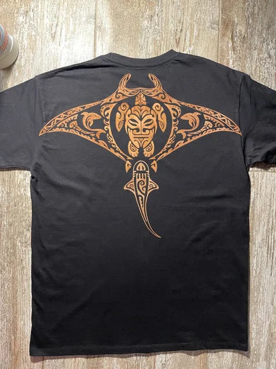 Back view of a black Polynesian T-shirt with a large hand-painted manta ray bleach art design