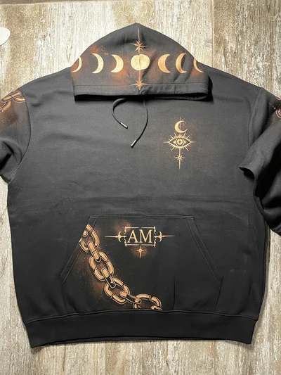 Vollständige Vorderansicht des schwarzen Hoodies mit himmlischem Auge auf der Brust, Kette und Initialen auf der Tasche und Mondphasen auf der Kapuze