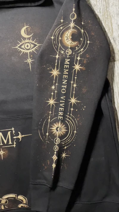 Video der Inschrift Memento Vivere und der himmlischen Bleach Art auf dem linken Ärmel eines schwarzen Hoodies