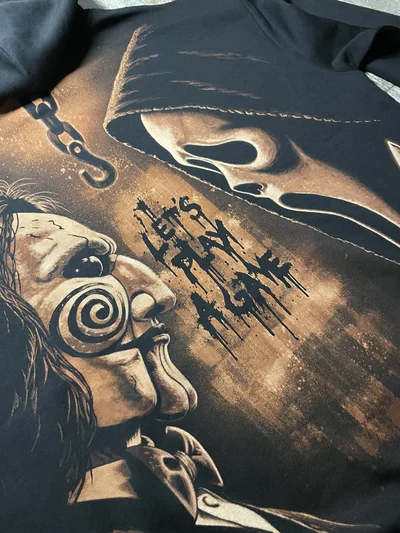 Close up of Ghostface and Billy the Puppet in a detailed horror design created with bleach on black hoodie fabric