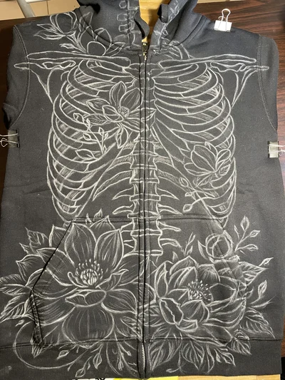 Chalk sketch of skeleton and magnolia flowers on the front of zip hoodie