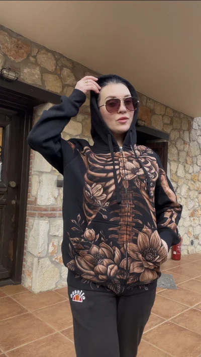 Model wearing hand painted skeleton and magnolia zip hoodie in daylight