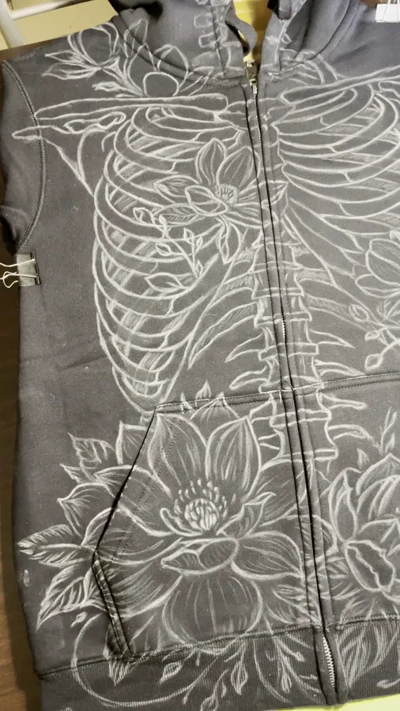 Video showing the first stage chalk sketch of skeleton and magnolia design on hoodie