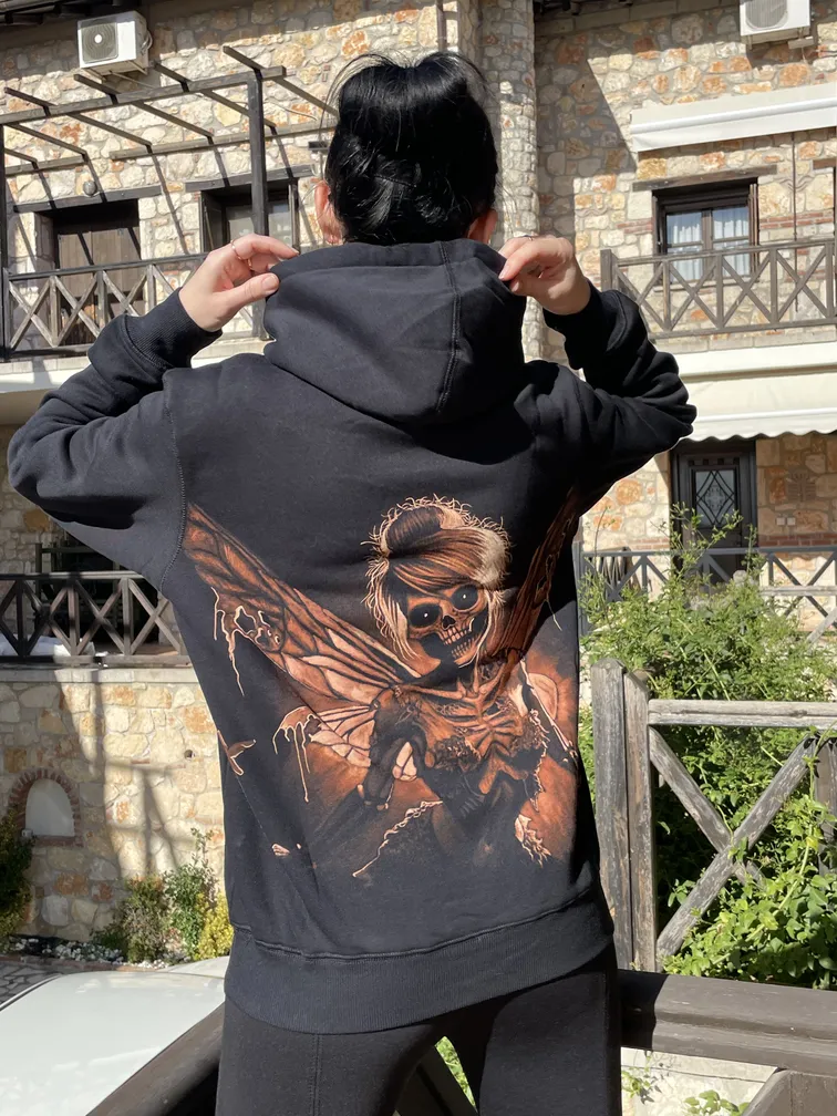 Close-up of a skeleton fairy illustration on a bleach art hoodie worn by a model