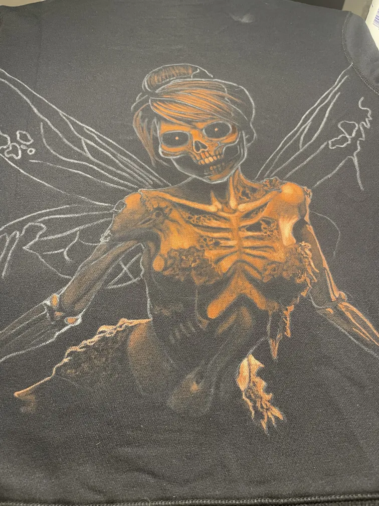 Work in progress of a skeleton fairy illustration painted with bleach on a fleece hoodie