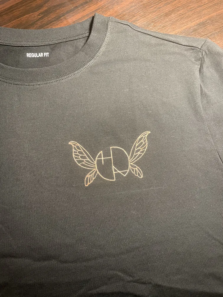 Front view of a t-shirt with Helen Oben Art logo and fairy wings detail