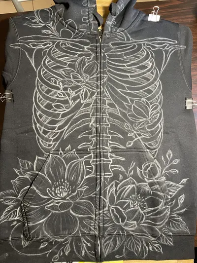 Chalk sketch of skeleton and magnolia flowers on the front of zip hoodie