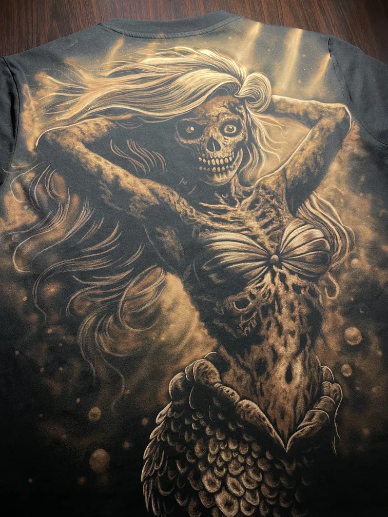 Angled view of a skeleton mermaid bleach art design on the back of the t-shirt
