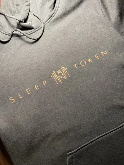 Close-up of the front of a black fleece hoodie with Sleep Token inspired text and logo