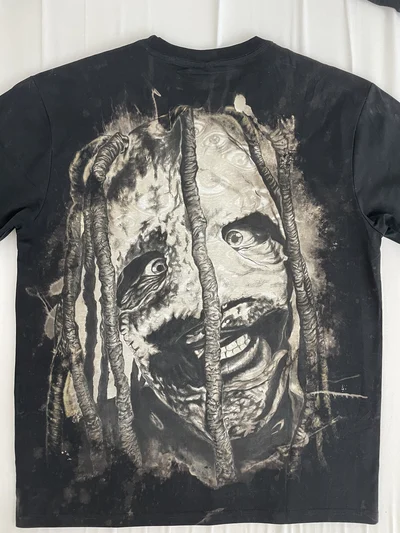Full back view of a black Slipknot T-shirt with a hand-painted Corey Taylor portrait on a bleached background