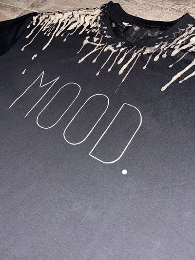 Close-up front detail of MOOD text on handmade bleach painted black raccoon tee