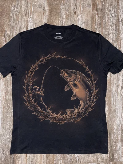 Hand painted t-shirt fishing shirt featuring an angler with a fishing rod and a mirror carp surrounded by circular water splashes on a black 100% cotton shirt