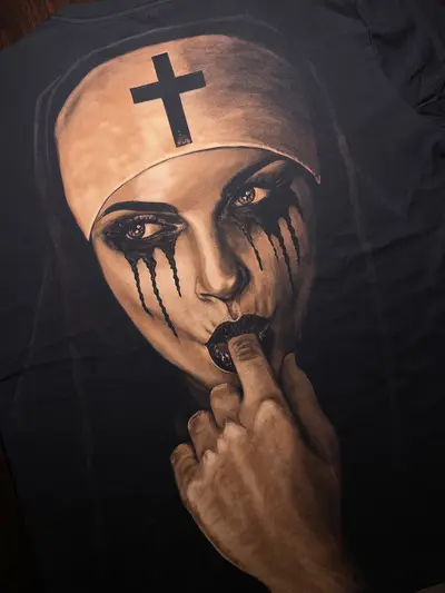 Close-up of hand painted bleach art nun with finger in mouth on T-shirt