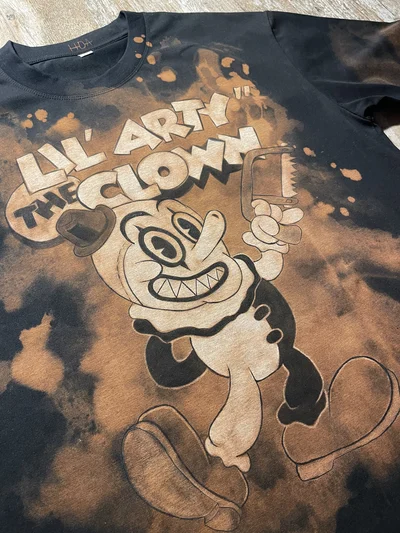 Angled front view of the Terrifier T-shirt with a hand-painted cartoon Art the Clown design
