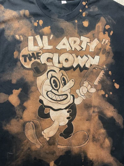 Close-up of the front design showing Lil’ Arty the Clown with a saw and Terrifying Tales lettering