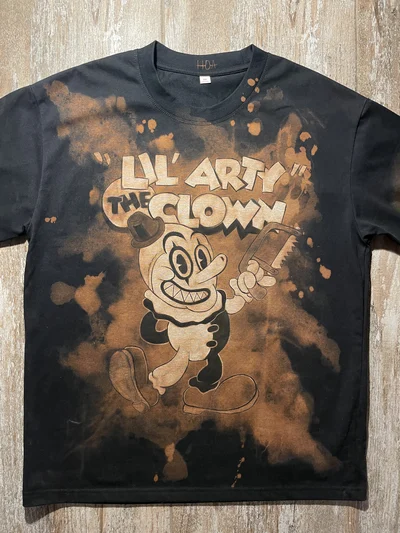 Full front view of the black Terrifier T-shirt with a miniature Lil’ Arty cartoon design