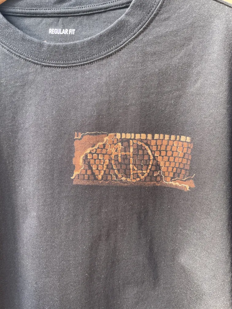 Detailaufnahme des Helen Oben Art Logos im Mosaik-Stil auf der Vorderseite eines T-Shirts