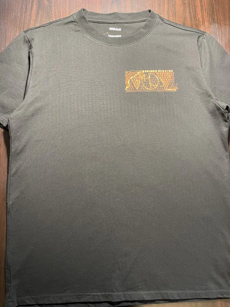 Frontansicht eines T-Shirts mit künstlerischem Logo im Mosaik-Stil