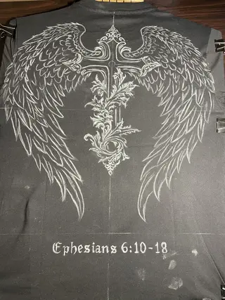 Chalk sketch of a gothic winged cross drawn on the back of a t-shirt before bleach painting