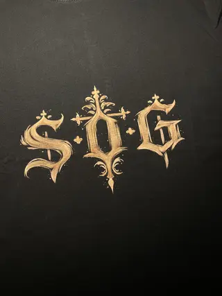 Close-up of S.O.G initials painted in gothic lettering on the front of the t-shirt